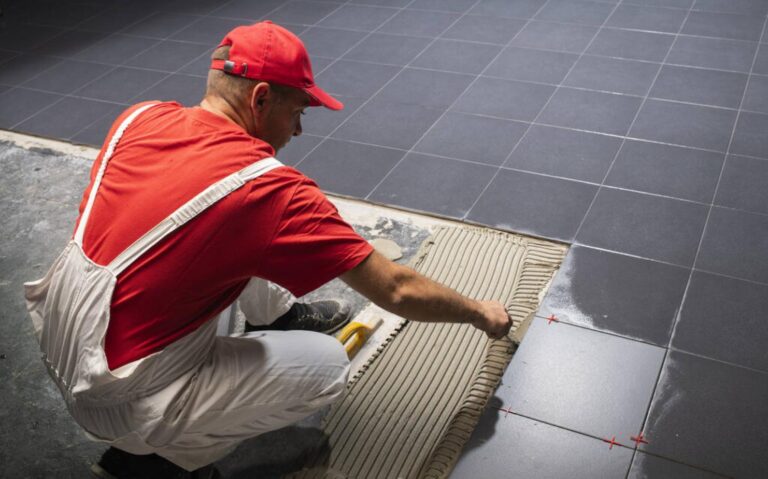 A construction worker putting on new floor tiles